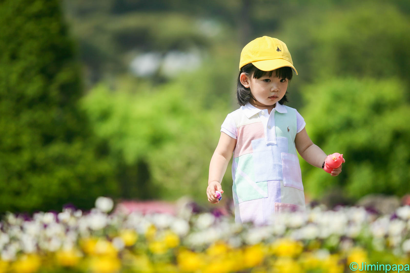 노란 모자를 쓰고 꽃밭에 서있는 아이