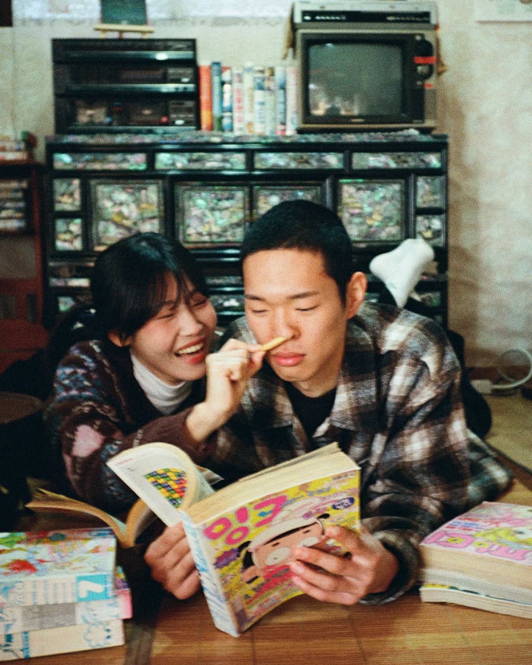 펜탁스17 PENTAX17로 촬영한 커플 스냅. 여자가 만화책을 보는 남자에게 장난을 걸고 있다.