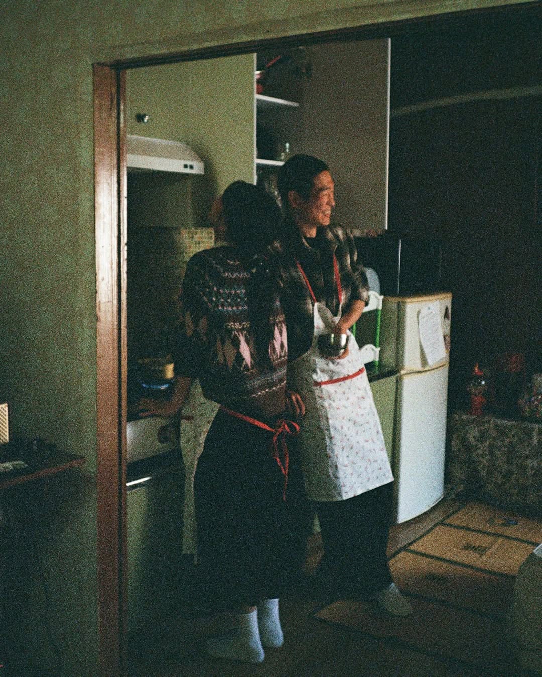 펜탁스17 PENTAX17로 촬영한 커플 스냅. 앞치마를 두른 커플이 주방에서 웃으며 요리를 하고 있다.