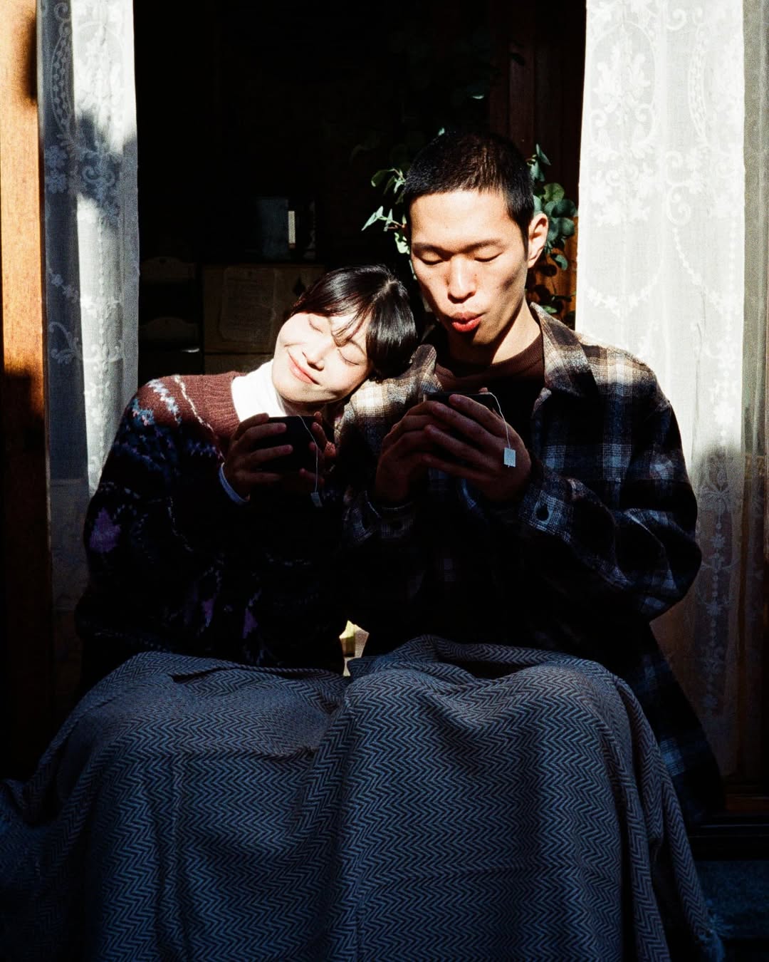 펜탁스17 PENTAX17로 촬영한 커플 스냅. 커플이 머그컵을 손에 쥐고 햇빛이 드는 마루에 앉아 있다. 여자는 남자의 어깨에 머리를 기대고 있고, 남자는 머그컵을 바라보고 있다.